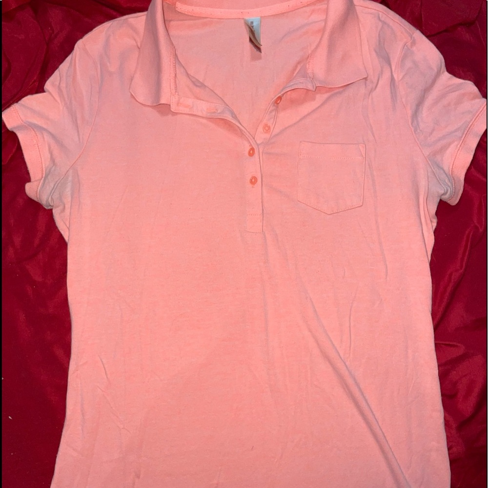 This is a coral colored polo shirt that is a size medium and is “No Boundaries”